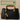 Black handbag with a gold cat charm and tassel in front of a 'Feline Fancy' sign.