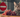 a cat sitting near a bunch of grapes with a warning sign