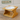 Wooden pet feeding station with a white bowl on a wooden floor.