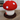 Stuffed mushroom toy with red cap and white spots on a wooden floor.