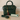 Green handbag with gold accents and a tassel charm on a beige surface, accompanied by a 'Feline Fancy' tag.