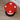 Red mushroom-shaped cushion with white spots on a wooden floor