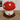 Mushroom-shaped stool with red cap and white spots on a wooden floor.