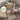 Person writing a handwritten gift note with a pen, next to a brown paper bag and envelope.