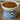 White bowl with blue checkered base filled with dog food on a wooden surface