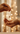 Hand holding a necklace with another hand reaching out against a softly blurred background of lights.