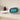 White and blue handheld device on a shelf with decorative items
