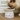 Cat eating from a white ceramic bowl with cat illustrations on a wooden surface.