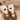 Brown shoes with white socks featuring black cat designs, held against a beige fabric background.