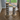 Two striped cat towers on a wooden floor with a window in the background.