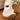 White sock with black cat design worn with brown fuzzy slippers on a wooden floor.